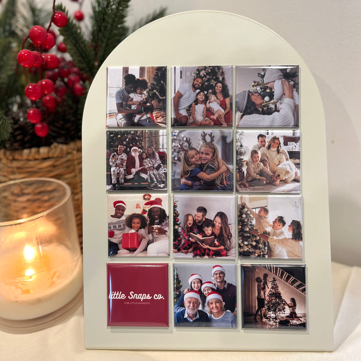 A beautiful display of custom/personalised photo magnets of Christmas family time, are presented on a magnet board. With Christmas decorations and a candle with little snaps co branding.
